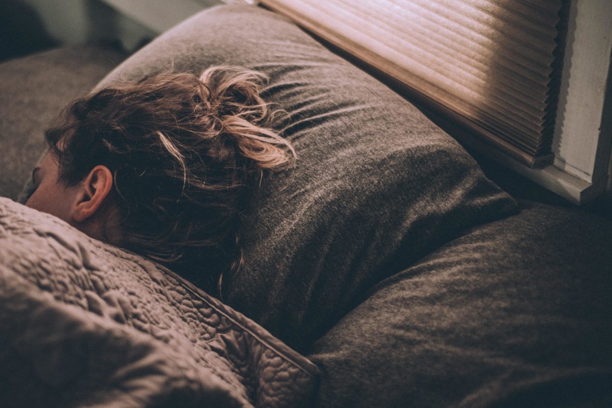 person with longer hair resting their head on a pillow